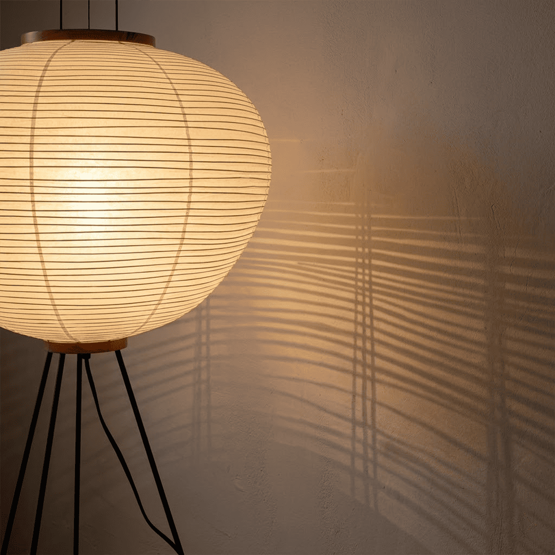 Stuber premium handcrafted off-white washi paper tripod floor lamp with black legs illuminating a modern Japandi living room.
