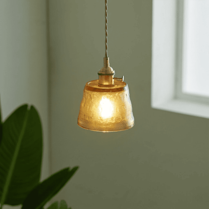 Amber glass pendant light hanging near indoor plant warm glow lifestyle