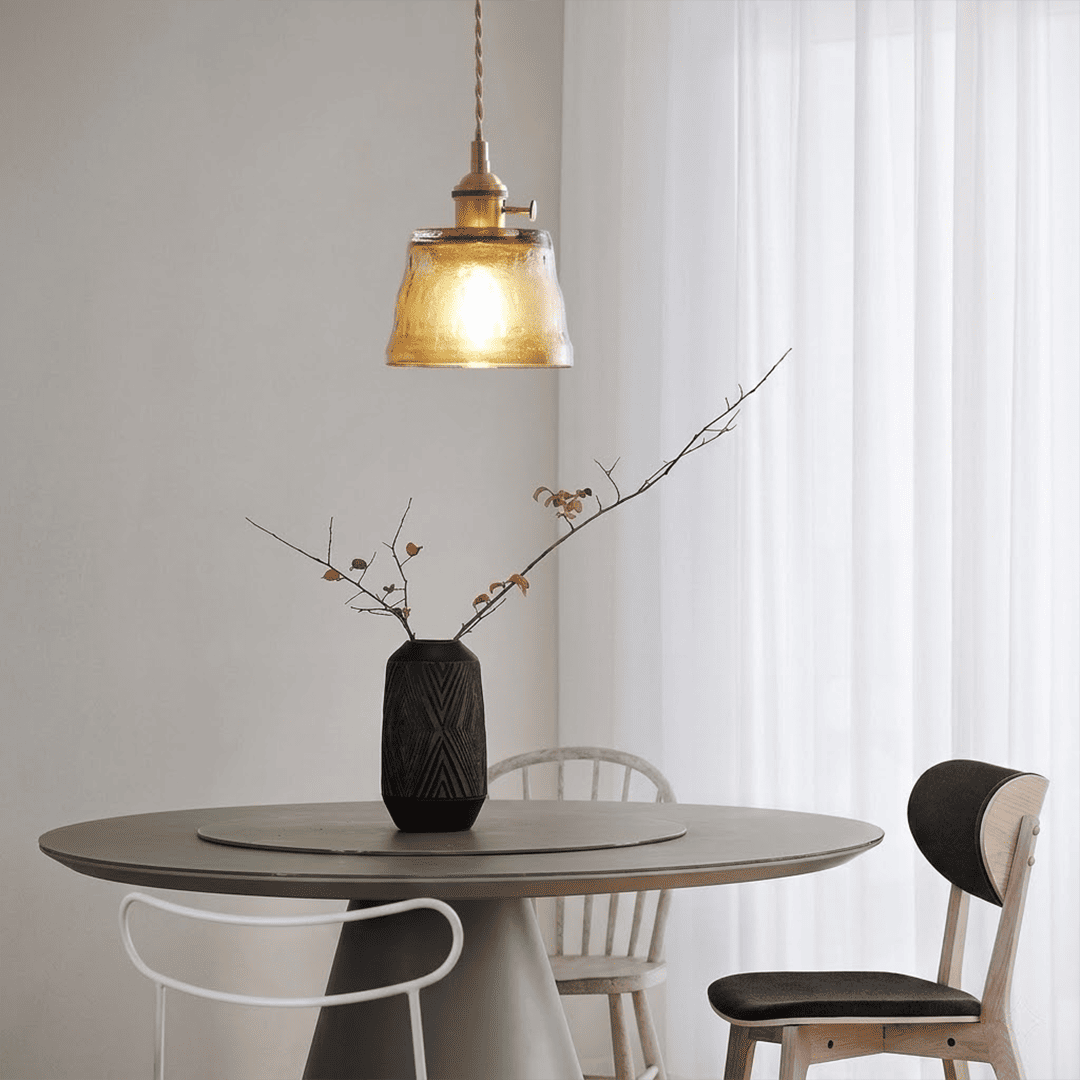 Amber glass pendant light hanging near indoor plant warm glow lifestyle