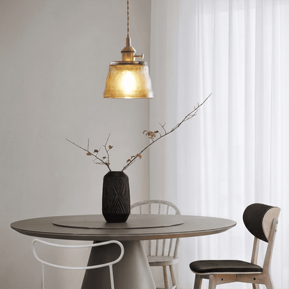 Amber glass pendant light hanging near indoor plant warm glow lifestyle