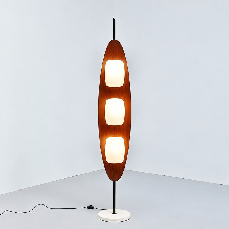 Tavola teak wood floor lamp with three shades standing beside a sofa in a mid-century living room