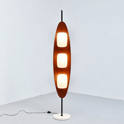 Tavola teak wood floor lamp with three shades standing beside a sofa in a mid-century living room