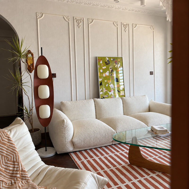 Tavola wood floor lamp standing beside a sofa as a warm sculptural centerpiece in a living room