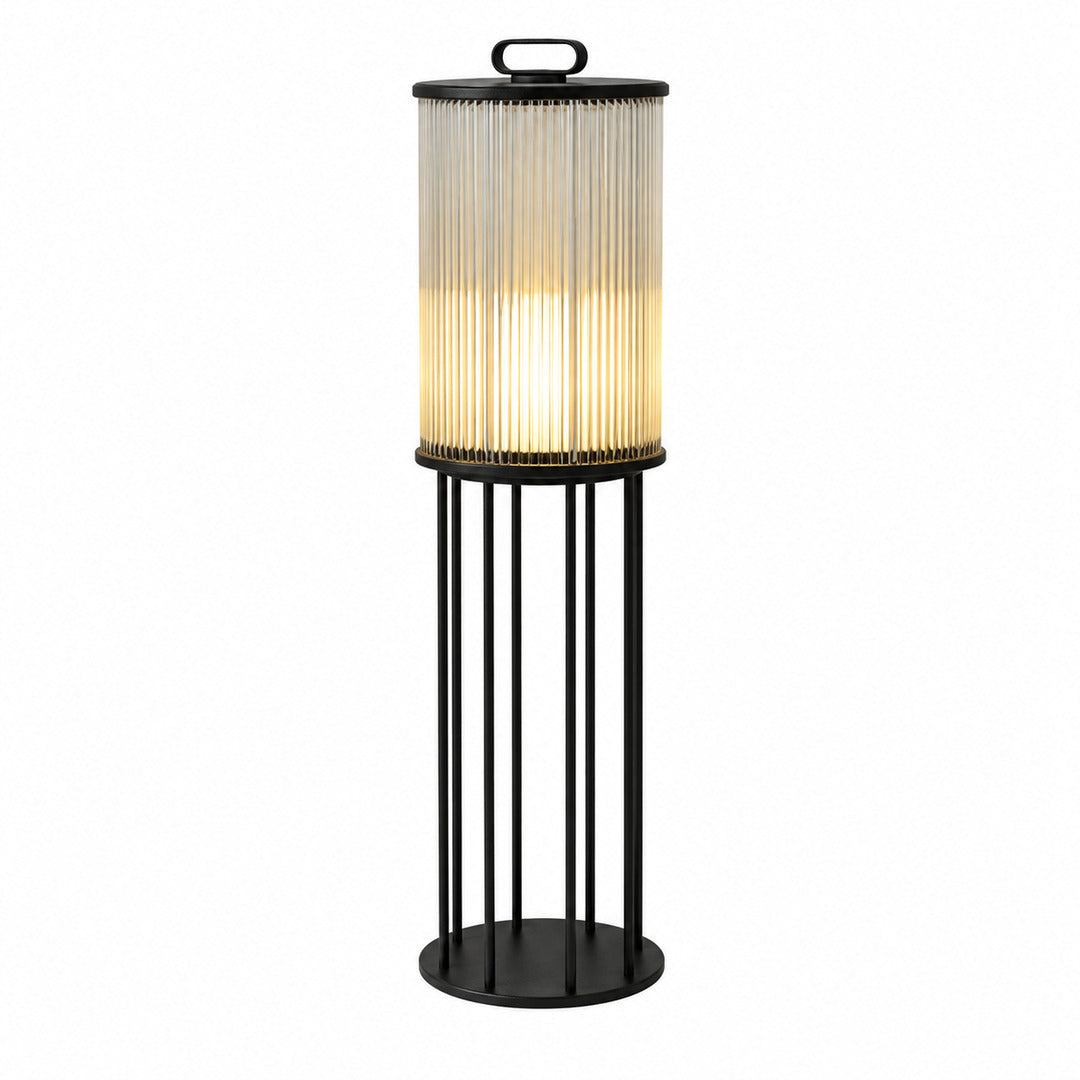 Torre outdoor garden light with a cylindrical frosted-glass body glowing warm on a garden lawn