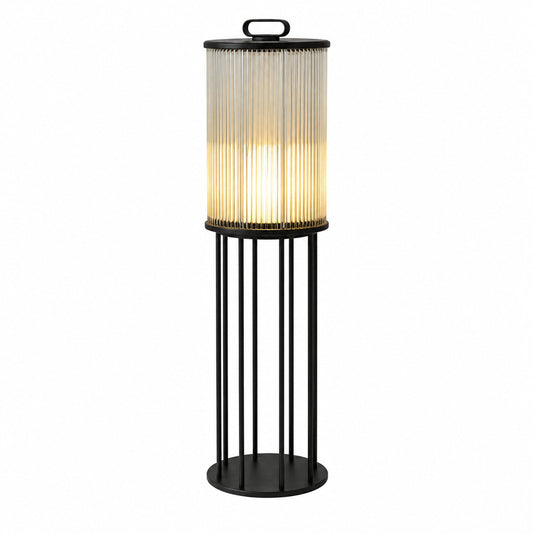 Torre outdoor garden light with a cylindrical frosted-glass body glowing warm on a garden lawn