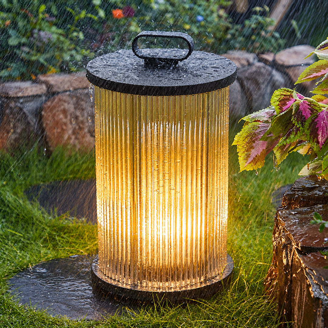 Torre outdoor garden lights lining a garden lawn with a warm cylindrical glow at dusk