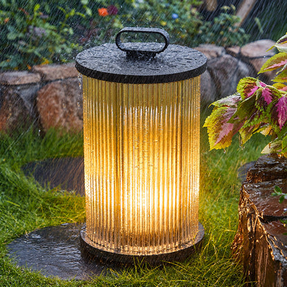 Torre outdoor garden lights lining a garden lawn with a warm cylindrical glow at dusk
