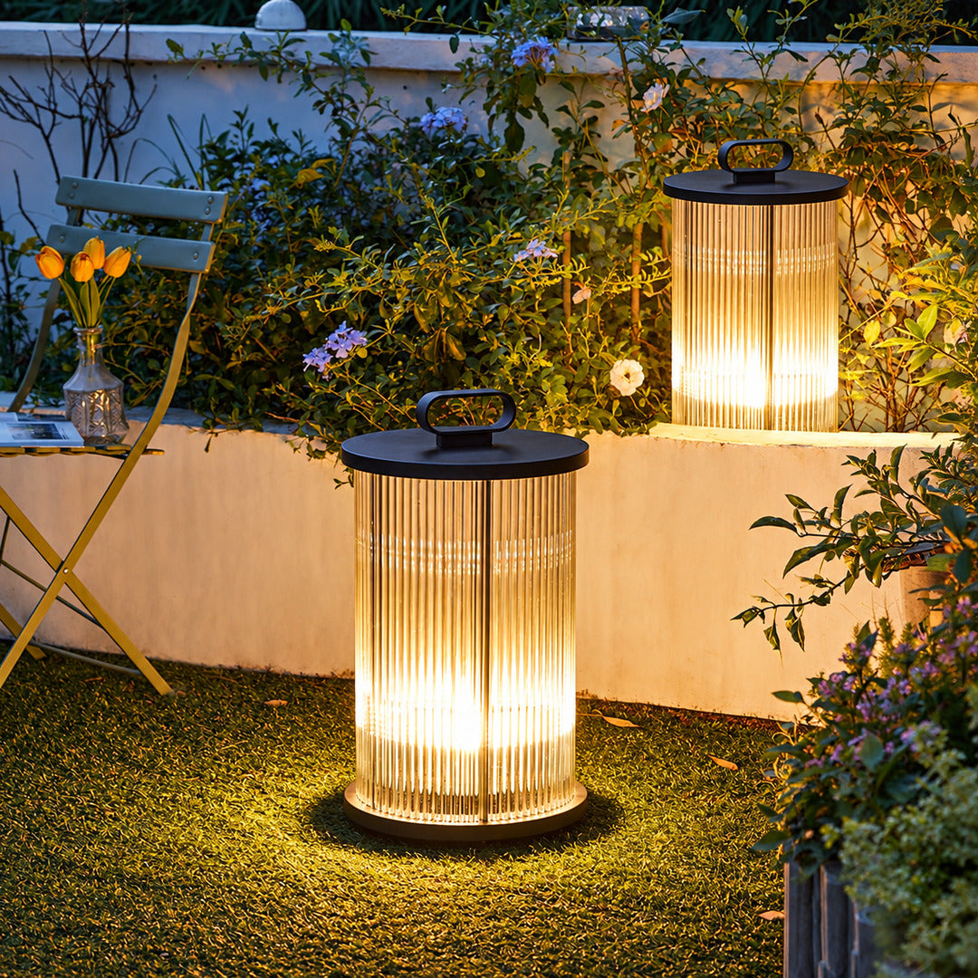 Torre outdoor garden lights lining a garden lawn with a warm cylindrical glow at dusk