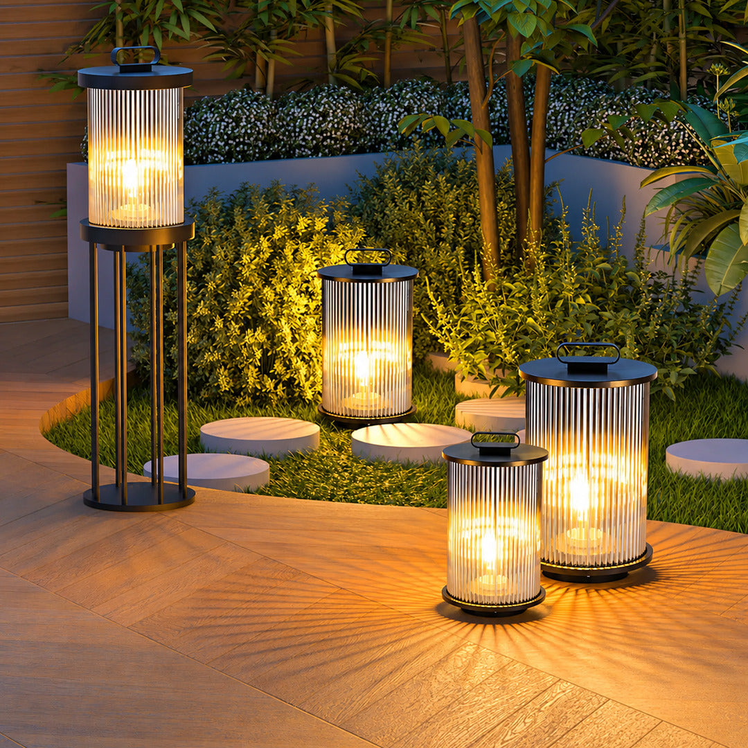 Torre outdoor garden lights lining a garden lawn with a warm cylindrical glow at dusk