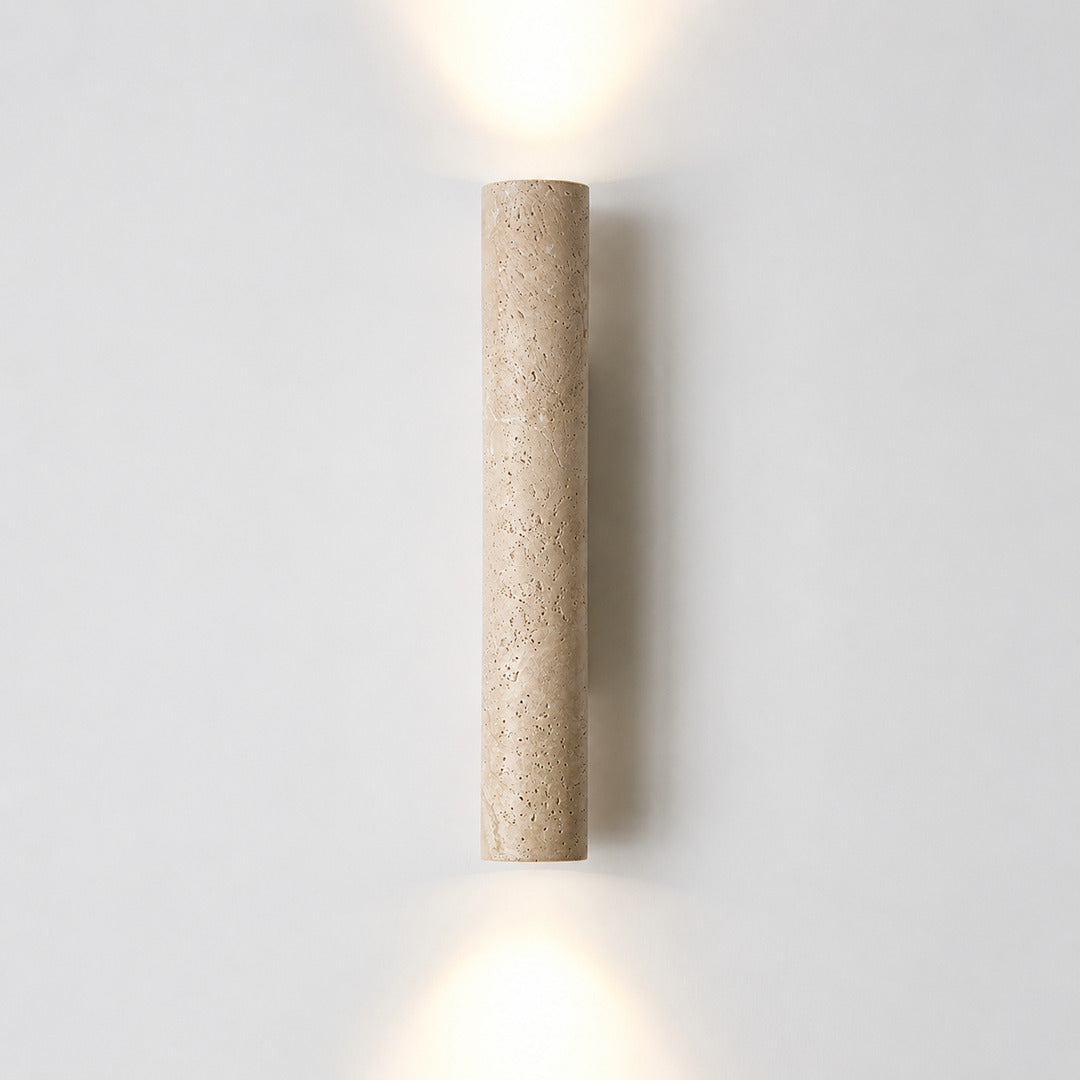 Torre travertine wall sconce illuminated warm amber glow natural travertine stone column wall white background