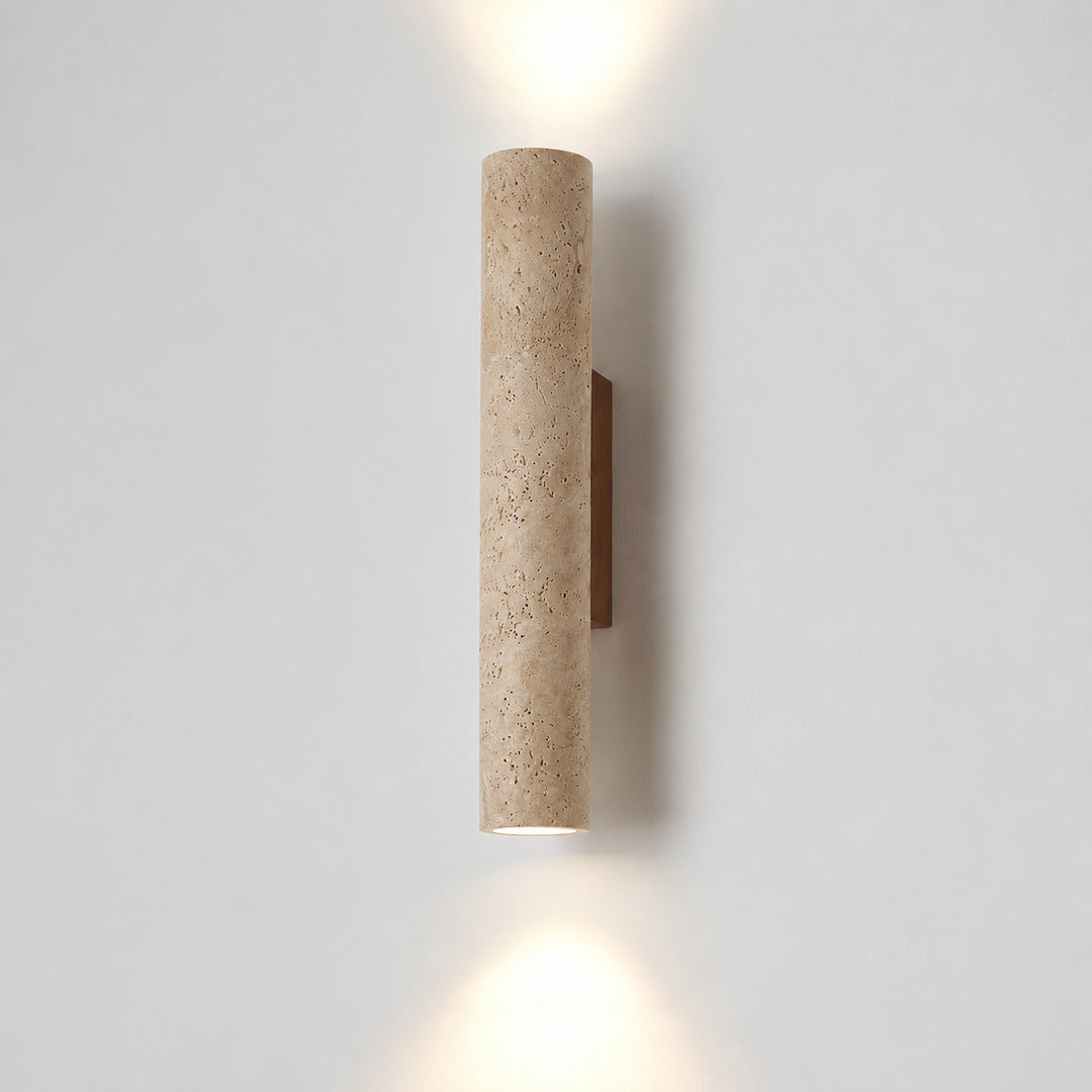 Torre travertine wall sconce illuminated warm amber glow natural travertine stone column wall white background
