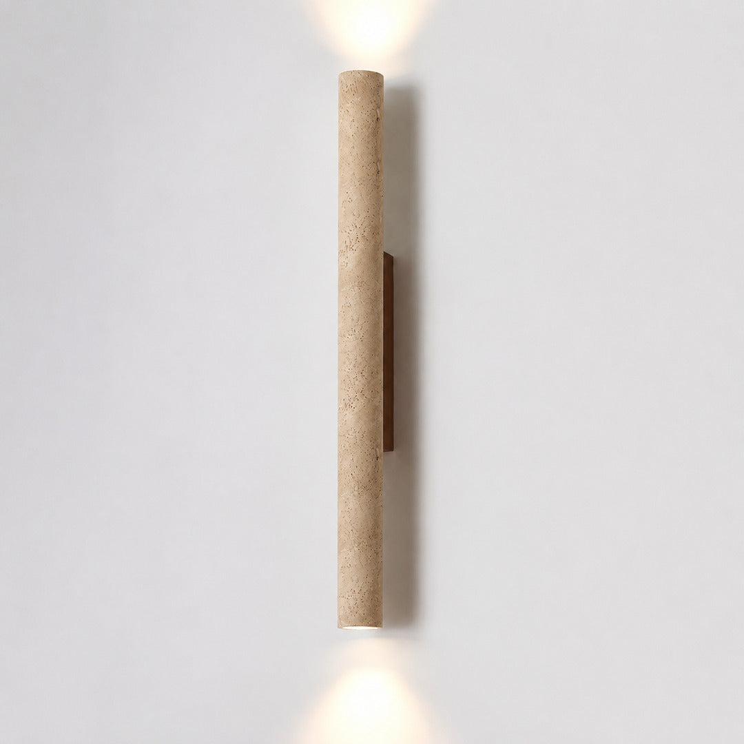 Torre travertine wall sconce illuminated warm amber glow natural travertine stone column wall white background