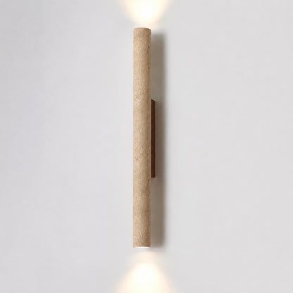 Torre travertine wall sconce illuminated warm amber glow natural travertine stone column wall white background