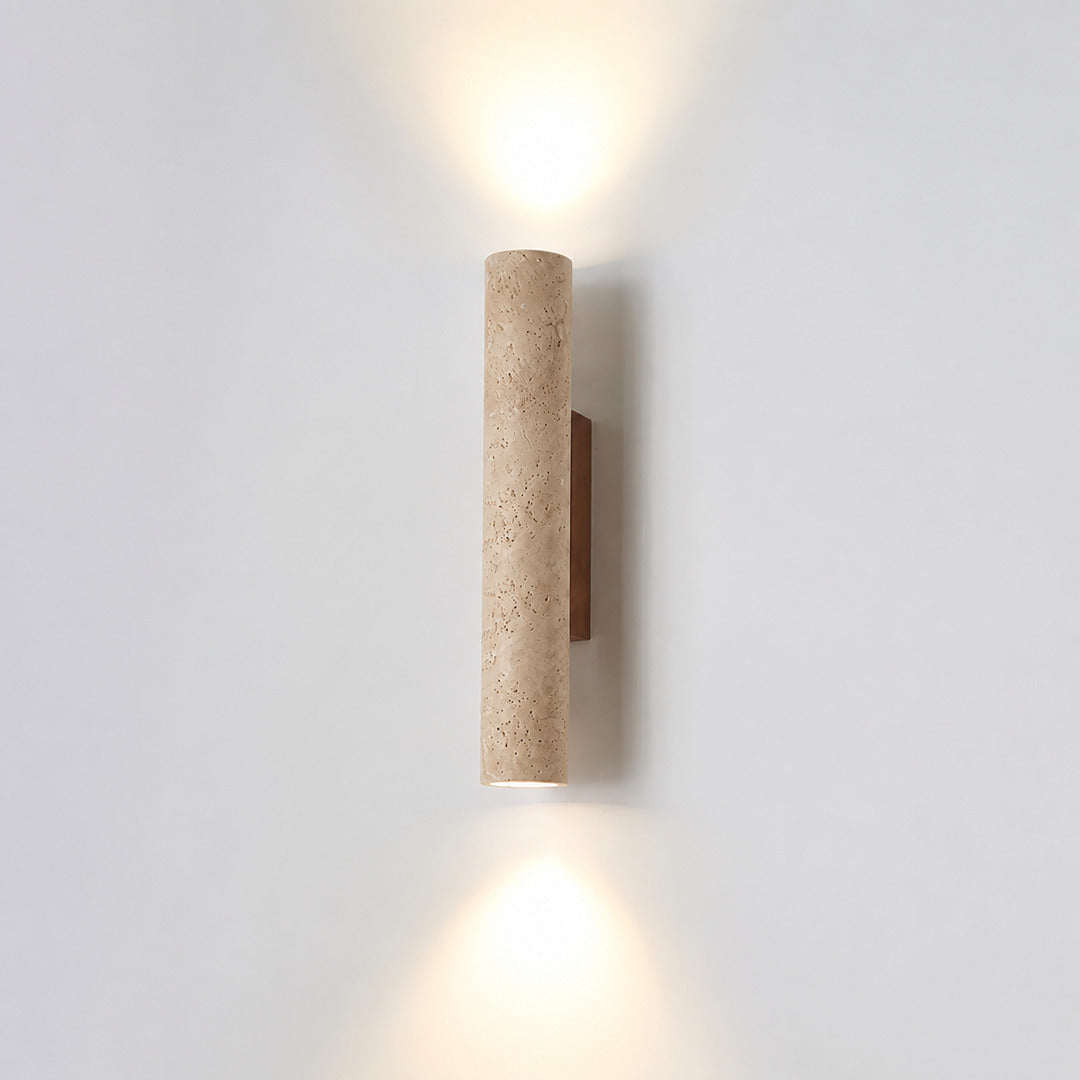 Torre travertine wall sconce illuminated warm amber glow natural travertine stone column wall white background