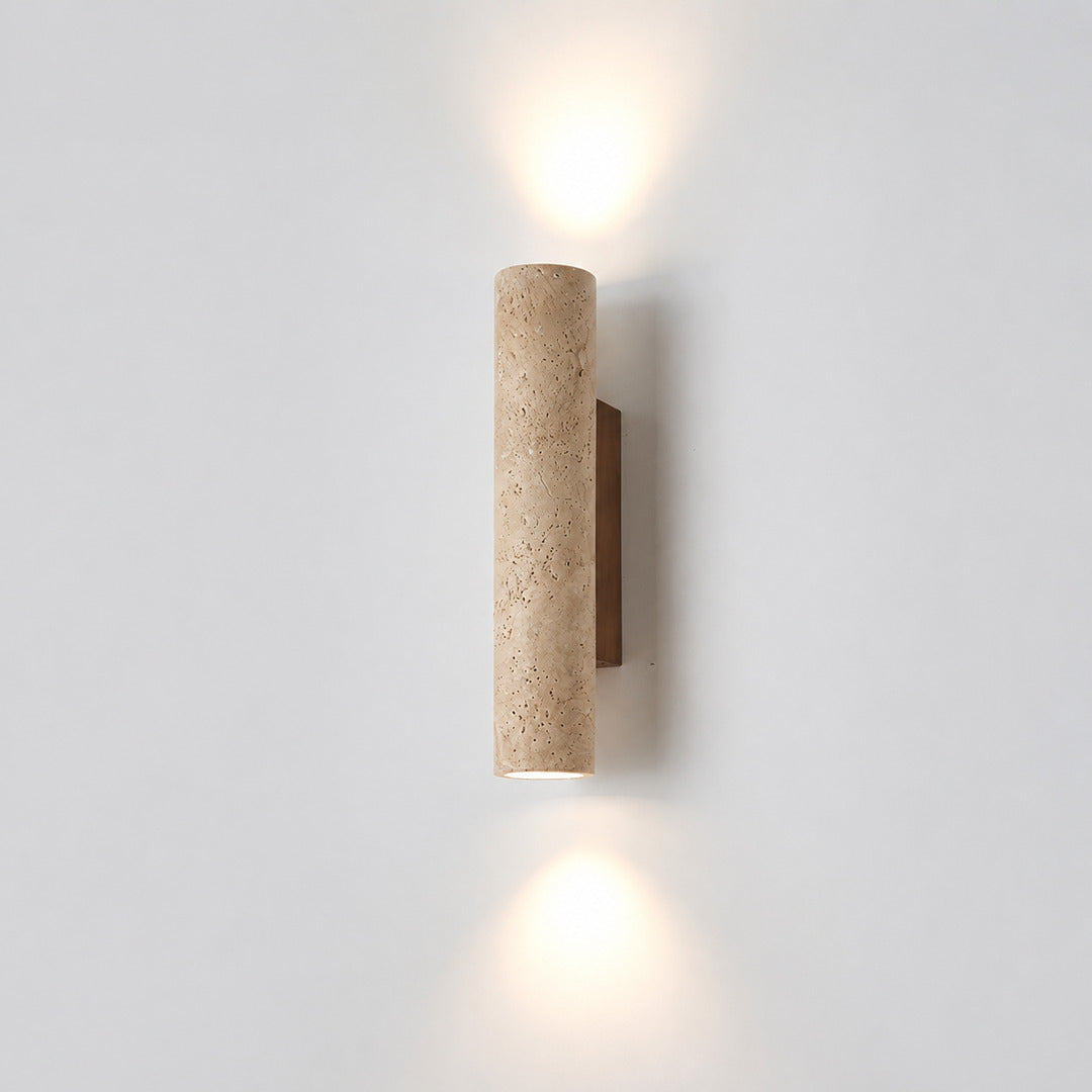 Torre travertine wall sconce illuminated warm amber glow natural travertine stone column wall white background