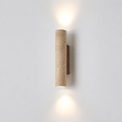 Torre travertine wall sconce illuminated warm amber glow natural travertine stone column wall white background