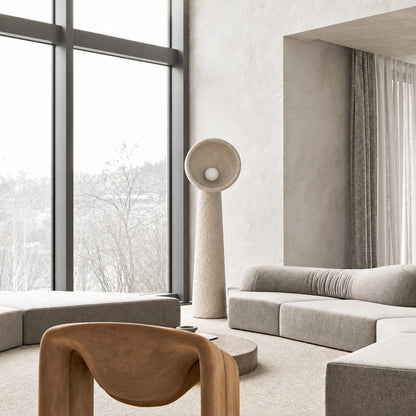 Totem sculptural floor lamp standing beside a sofa as a soft sculptural accent in a living room