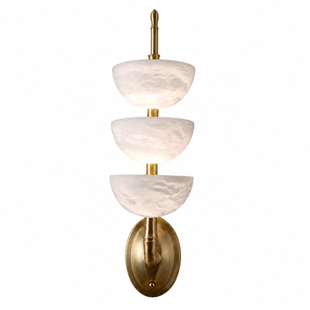 Trio alabaster wall sconce with three vertical natural stone tube shades glowing warm on a wall