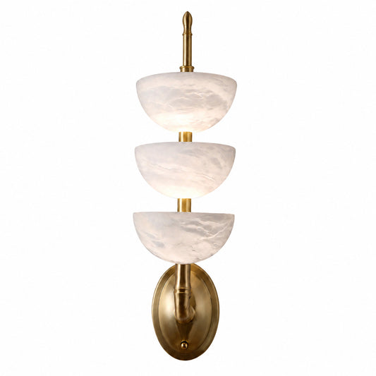 Trio alabaster wall sconce with three vertical natural stone tube shades glowing warm on a wall