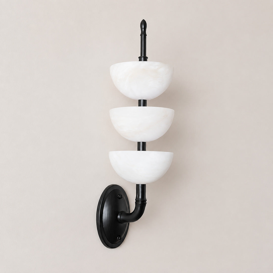 Black-frame Trio alabaster wall sconce as a modern accent on a bedroom wall