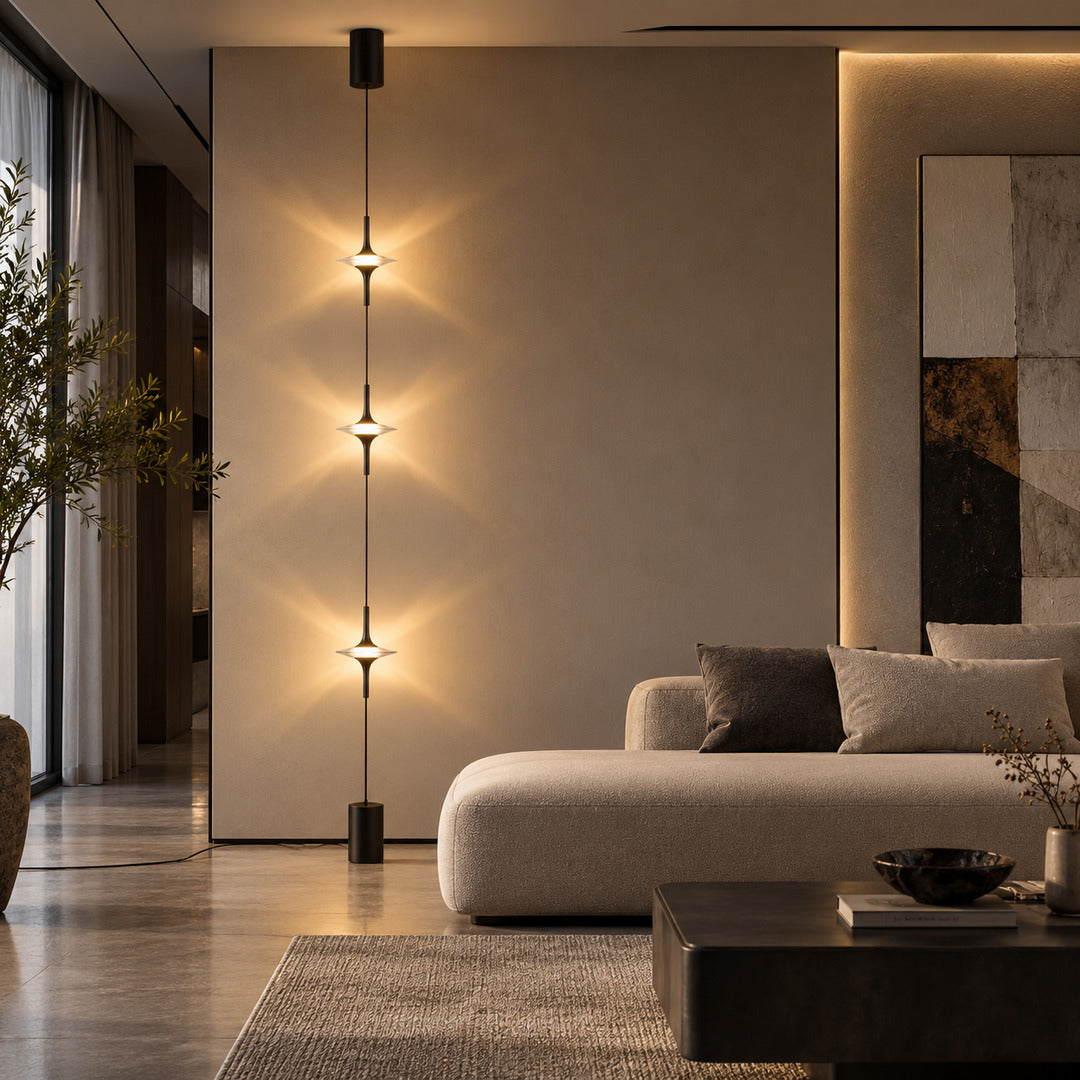Black Trottola lamp behind a low sofa creating a column of star light on a plain wall