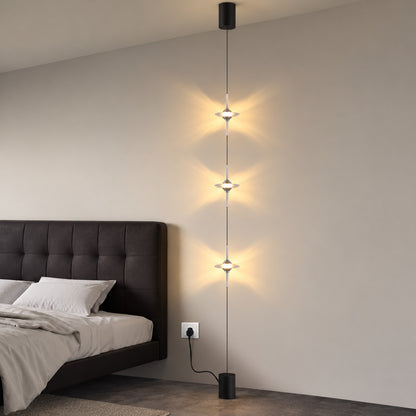 Black Trottola floor to ceiling lamp beside the bed casting soft star light over the nightstand