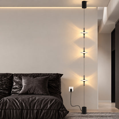 Black Trottola lamp behind a low sofa creating a column of star light on a plain wall