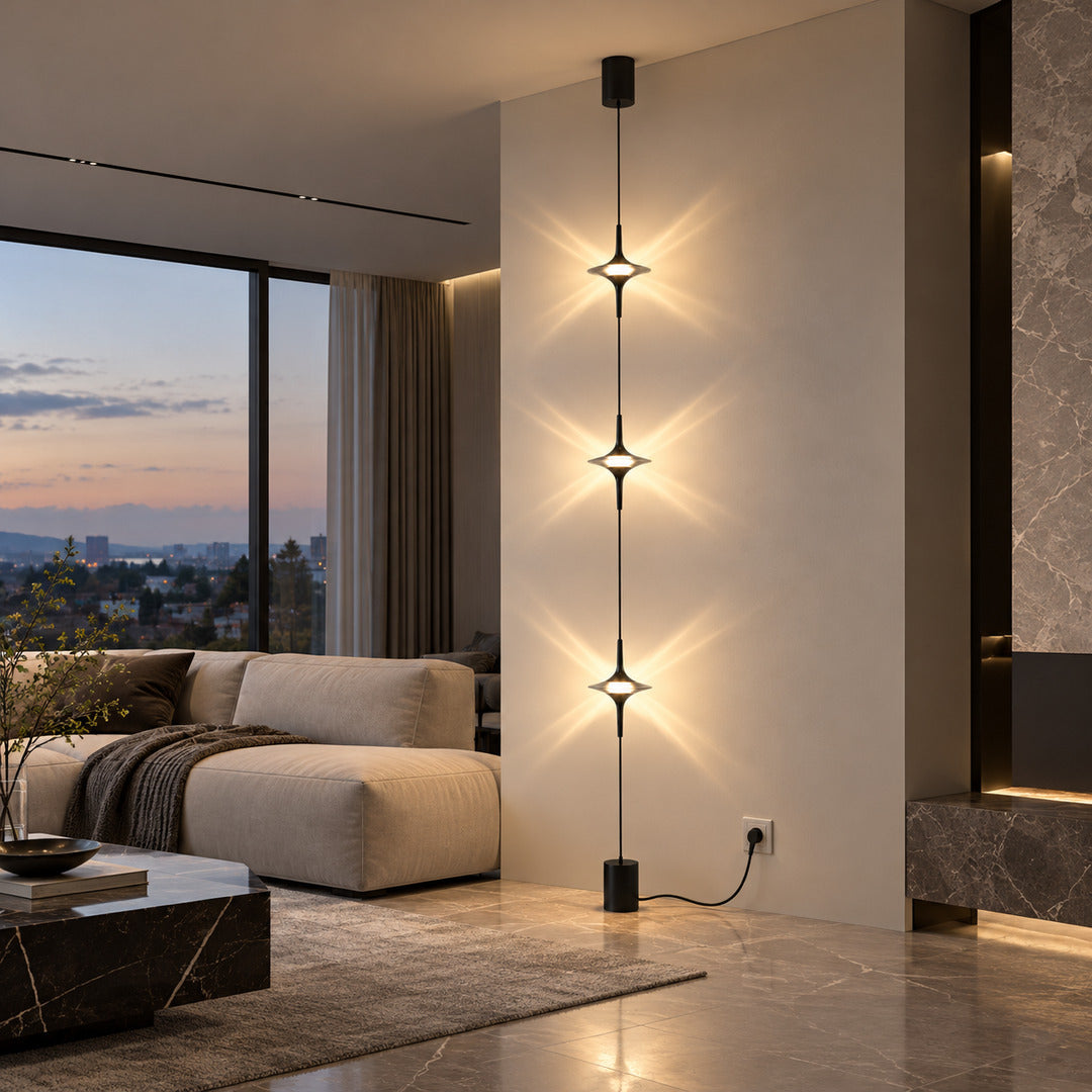 Chrome Trottola floor to ceiling lamp beside a sofa casting star-shaped light on the wall