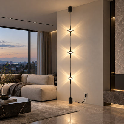 Chrome Trottola floor to ceiling lamp beside a sofa casting star-shaped light on the wall