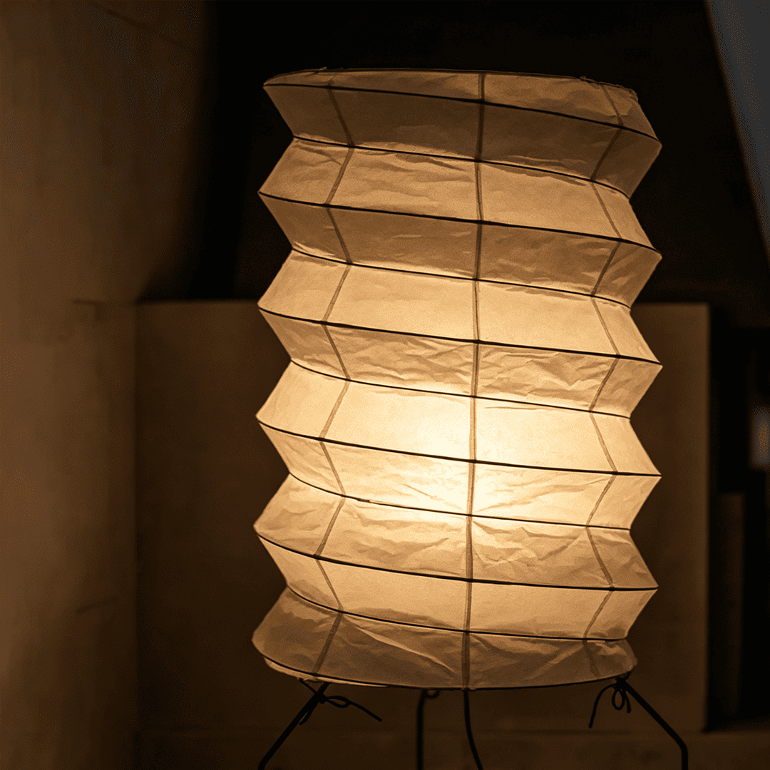 UF2-31N Washi paper table lamp with warm internal glow, handcrafted rice paper shade on black metal tripod legs.