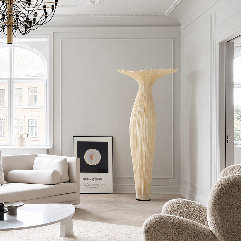 Vaso fabric floor lamp standing beside a sofa as a warm sculptural accent in a living room