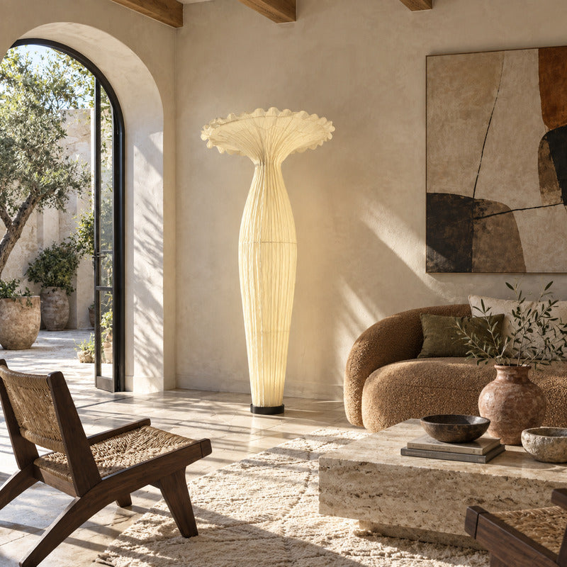 Vaso fabric floor lamp standing beside a sofa as a warm sculptural accent in a living room