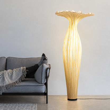 Vaso fabric floor lamp standing beside a sofa as a warm sculptural accent in a living room