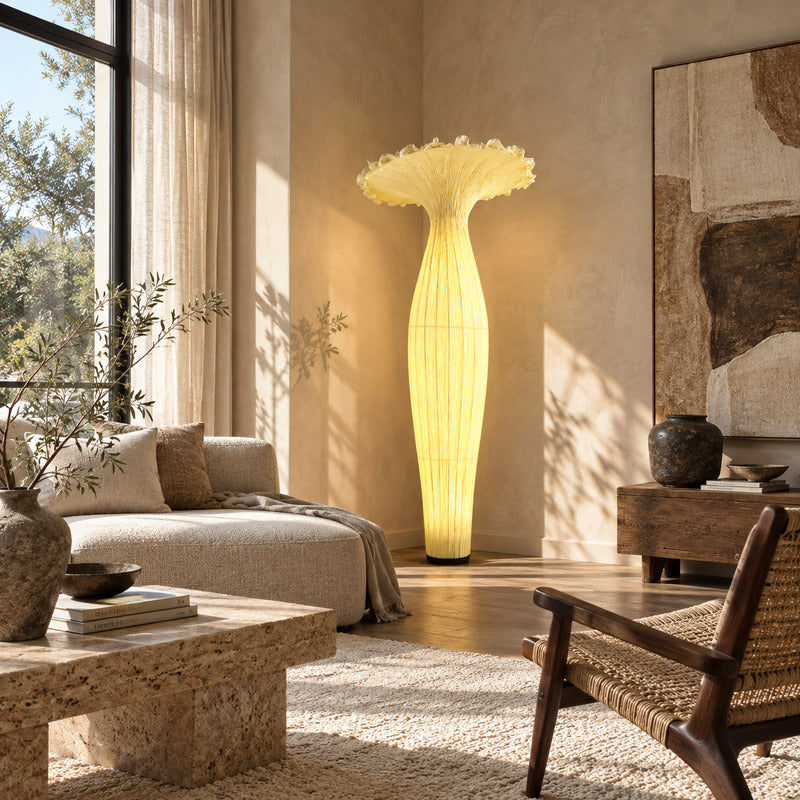 Vaso fabric floor lamp standing beside a sofa as a warm sculptural accent in a living room