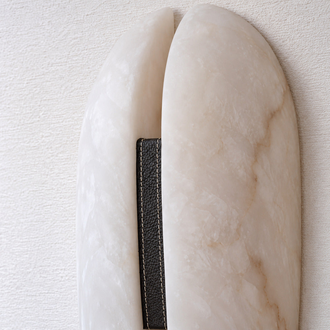 Detail of the dark leather accent band at the center of the Velo alabaster sconce