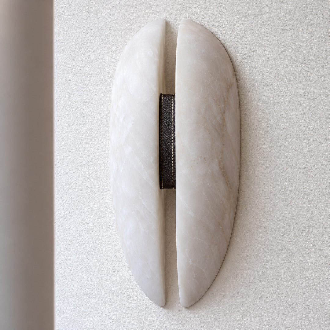 Velo wall sconce with white alabaster panels, black frame and dark leather band on a white background