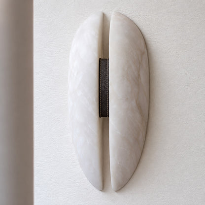 Velo wall sconce with white alabaster panels, black frame and dark leather band on a white background