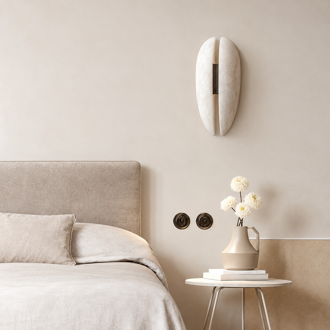 Velo alabaster wall sconce above a nightstand providing soft reading light