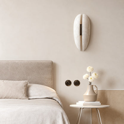 Velo alabaster wall sconce above a nightstand providing soft reading light