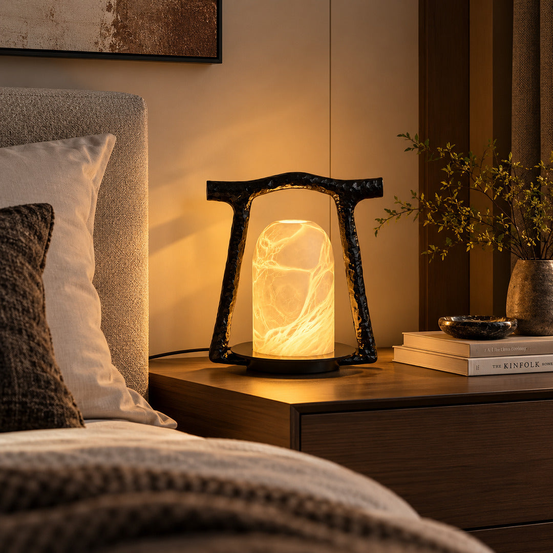 Volta alabaster table lamp casting a soft glow on a bedside table