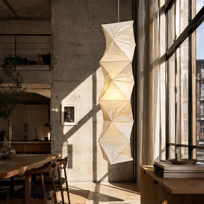 Close-up of an origami-inspired Washi Paper L8 Hanging Lamp in a rustic loft near a sunlit wooden table by Stuber Lighting.