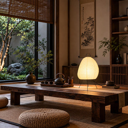 Illuminated washi paper tall tripod table lamp styled on a low wooden tea table in a serene Japandi tatami room