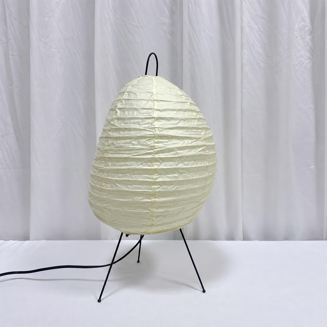Unlit white washi paper tall tripod table lamp displaying its organic lantern texture on a clean white desk
