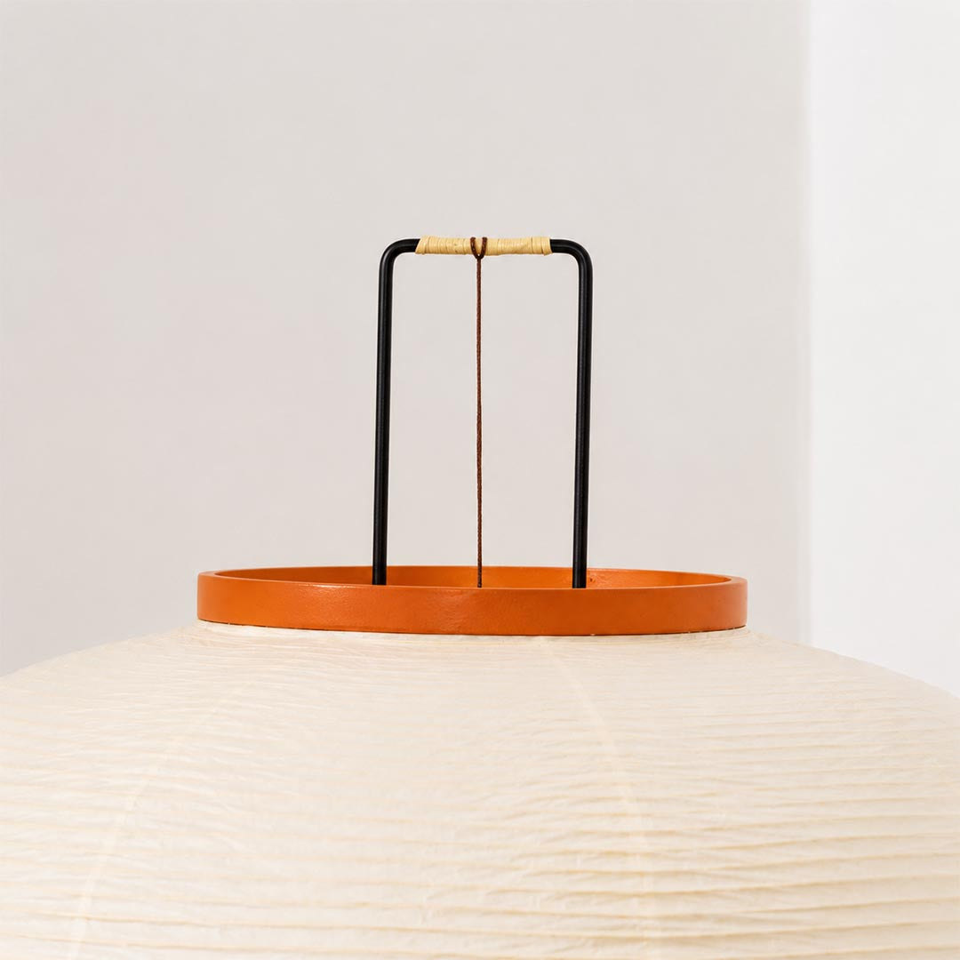 Close-up view of a washi paper tripod floor lamp shade showing warm glow and orange wooden top detail by stuberlighting