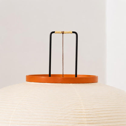 Close-up view of a washi paper tripod floor lamp shade showing warm glow and orange wooden top detail by stuberlighting