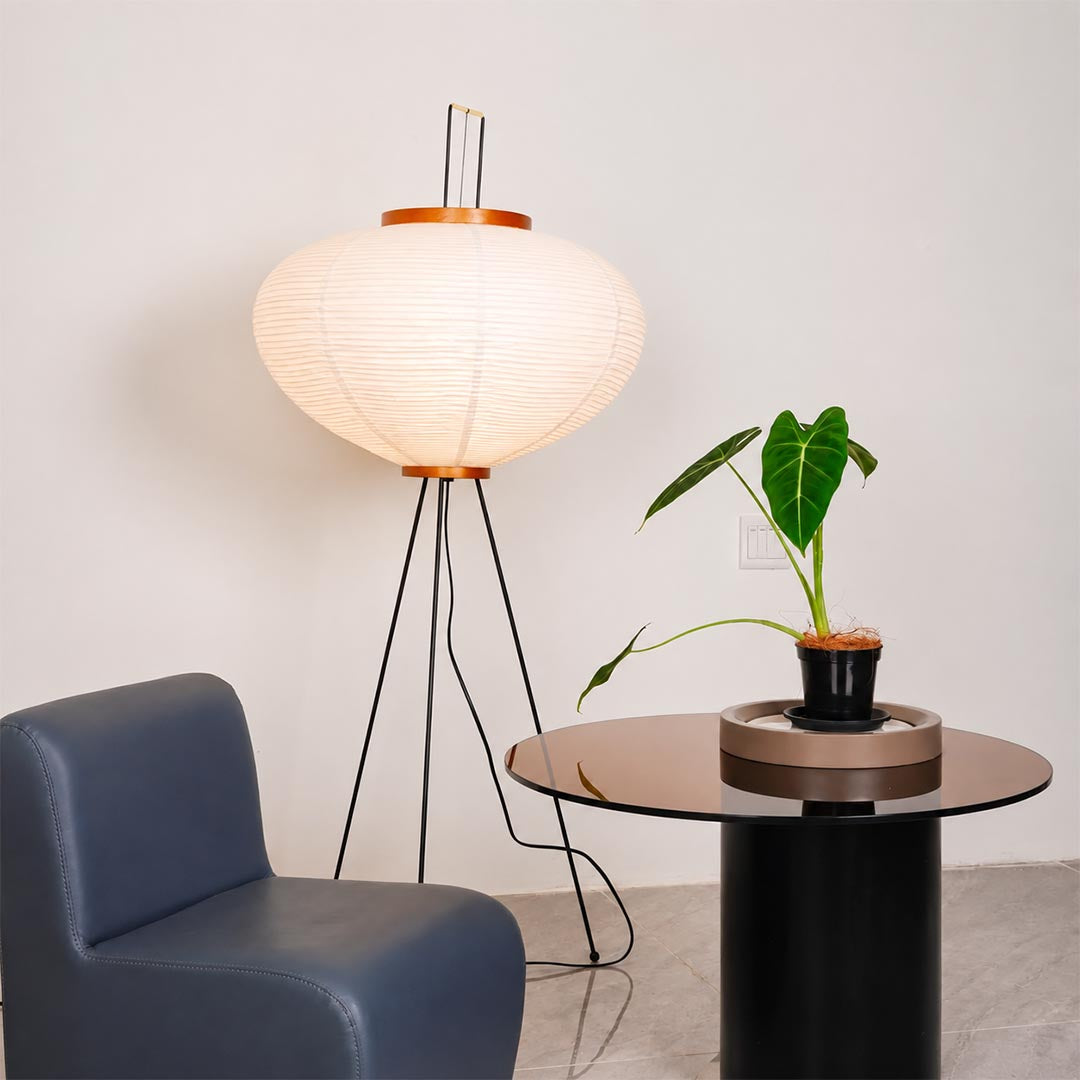 Close-up view of a washi paper tripod floor lamp shade showing warm glow and orange wooden top detail by stuberlighting