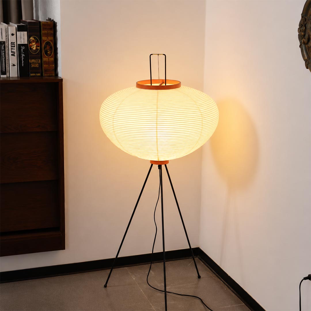 apanese style washi paper tripod floor lamp with black tripod legs illuminated on white background