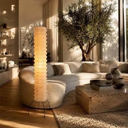 Ambient warm lighting from a tall Washi Paper UF4-31N Floor Lamp next to a curved white sectional sofa by Stuber Lighting.