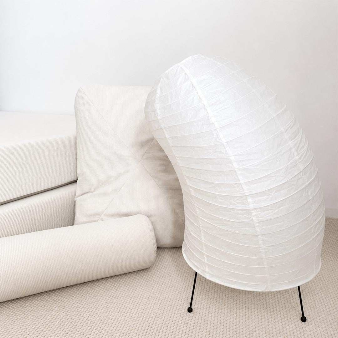 Aesthetic Washi Paper VB-13T Horn Lamp placed among white cushions and plush mattresses in a minimalist studio by Stuber Lighting.