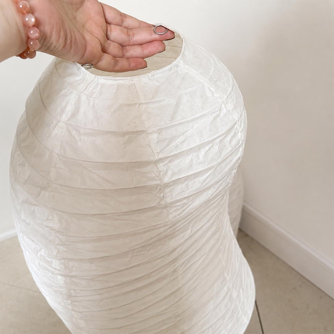 Hand touching the flexible, high-quality texturized shade of a Washi Paper VB-13T Lamp to show its genuine paper craftsmanship by Stuber Lighting.